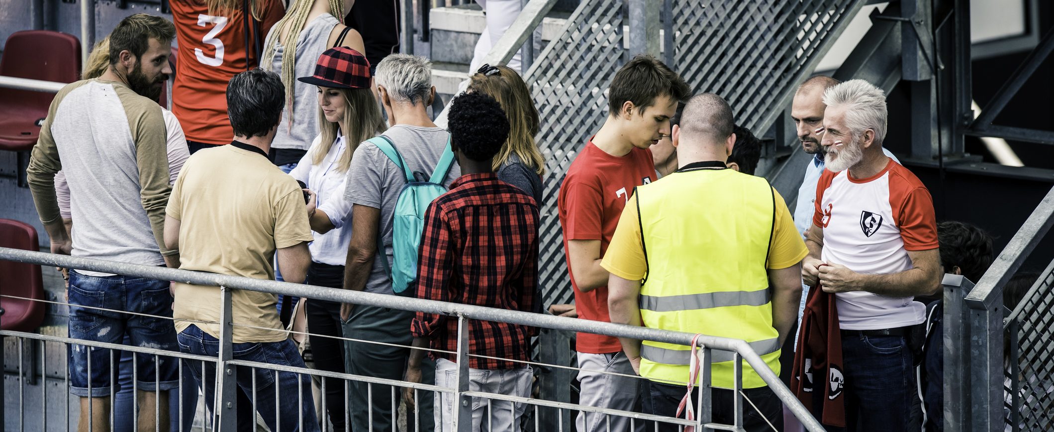 Sports fans walking up the stairs past a security guard onto the bleachers of a stadium.